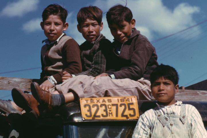 Boys sit on a truck at the Farm Security Administration’s Migratory Labor Camp in Robstown, Texas
