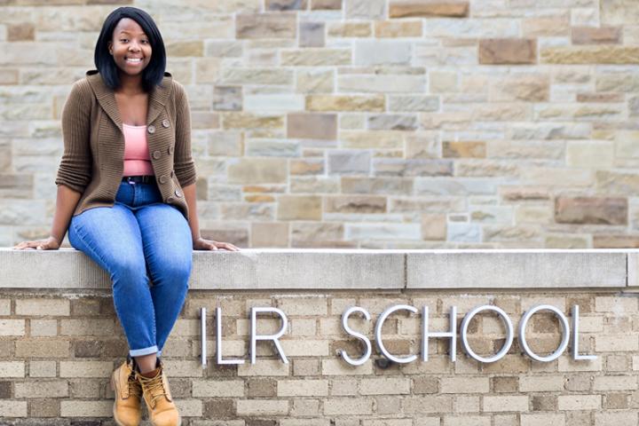 Grace Traore '20 sits on the ILR School sign outside of Ives Hall East. 