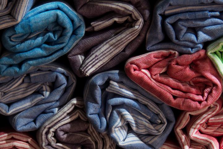 Photograph of rolled up garments of different colors.