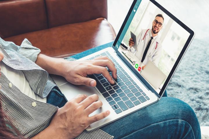 A couple speaking to a doctor online with a laptop computer.