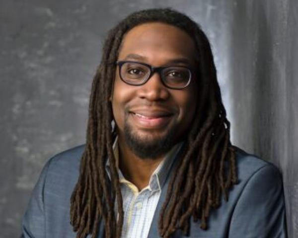 professional man smiles at camera with grey suit coat and white shirt