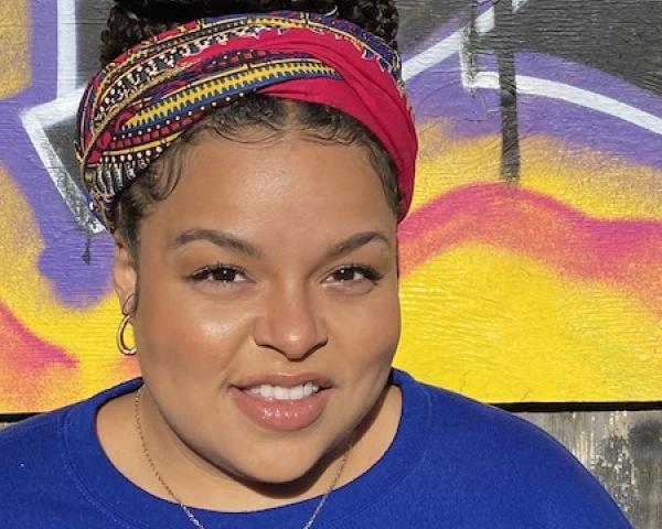 professional woman smiles at camera in front of mural