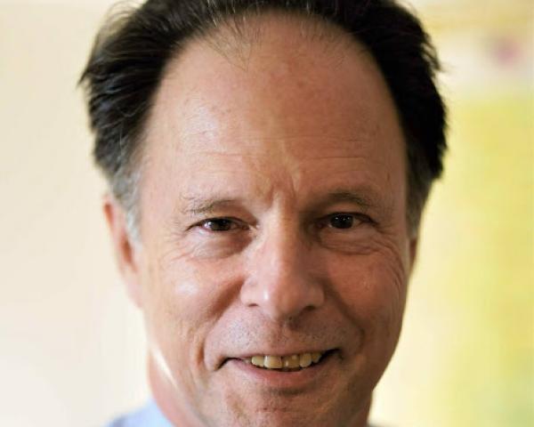 man in button shirt and tie smiles at camera