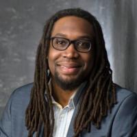 professional man smiles at camera with grey suit coat and white shirt